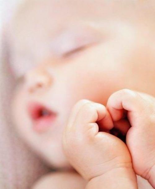 Newborn baby's hand grasping an adult's finger